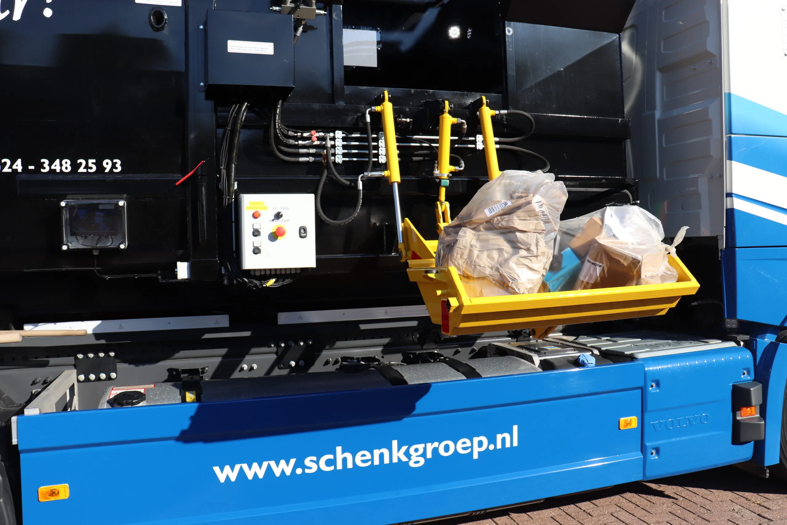 Detail van hydraulische en elektrische componenten op een IPC-truck, inclusief gele arm, bedieningskast en bekabeling